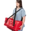Person wearing blue scrubs carrying a red Buscot Babevac evacuation cot using shoulder straps
