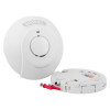 Smoke and carbon monoxide detector with detached mounting base showing wiring terminals. Front of the device includes a central test/silence button and indicators for “AC POWER” and “ALARM.”