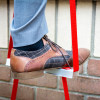 Close-up of a foot on the Hs2Stfel Hs3Stfel Ultrafire Fire Escape Ladder office step in situ against a wall