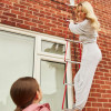 Woman climbing down Hs2Stfel Hs3Stfel Ultrafire fire escape ladder attached to a brick wall outside a house