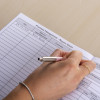Closeup of an open fire safety log book with a hand writing on a report sheet page