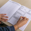 Open fire safety log book showing blank and partially filled pages with a person holding a pen