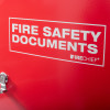 close up front of red metal document cabinet hasp lock showing part of text fire safety documents