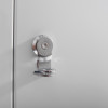 close up of a white metal document cabinet hasp lock showing its circular and hinged parts on a grey surface