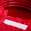 Close-up of a red hose reel cover showing a white velcro fastening strip attached to the fabric