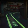 floor mounted escape route signs glowing on a dark floor showing direction in use