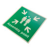 Assembly point sign rigid plastic showing three people icons with arrows pointing inward on a green background viewed at an angle