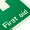 Close up of a first aid sign with text on rigid plastic showing part of the green and white design