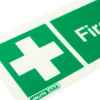 Close up of first aid equipment sign rigid plastic showing white cross on green background and part of the text First
