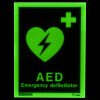 aed location sign showing a green glowing heart with a lightning bolt and text on a dark background