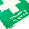 Close up of emergency equipment location sign rigid plastic with white cross on green background and white text