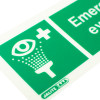 Close up of an emergency eye wash sign showing an eye with water spray symbol and a white cross on green background