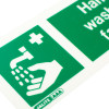 Close up of hand wash facility sign with text showing a hand under running water on rigid plastic sign