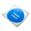 Angled view of a keep clear sign vinyl with blue circle and white text on a white background