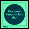 fire door keep locked shut sign on rigid plastic showing white text on a dark round background in dim light
