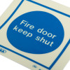 Closeup image of Js5421A Jalite Fire Door Keep Shut vinyl sign showing blue circle with white text on a light background