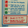 Closeup of a fire action sign showing safety instructions and warnings in red and blue text