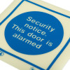 Closeup of the Js5480A Security Notice This Door Is Alarmed vinyl sign showing blue circle with white text on cream background
