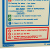 Closeup of fire action sign showing instructions and warnings in blue, green, and red text with symbols