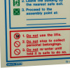 Closeup of fire action sign showing instructions in red text and symbols on white background