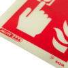 Close up of fire alarm id sign square showing part of a hand pressing a button symbol on a red and white background