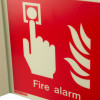 Closeup of jalite panoramic fire alarm location with text sign showing a hand pressing a button and flames symbol