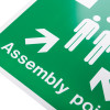close up of a white rigid plastic assembly point sign with text and arrows on a green background