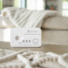 Kidde 2030-DCR Carbon Monoxide Alarm on a table with a beige sofa and blanket in the background