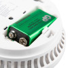 the back of a white circular smoke alarm showing a red 9 volt battery in the battery compartment