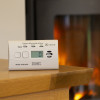 Kidde K10LLDCO 10 Year Digital Carbon Monoxide Alarm on a wooden table with a fireplace burning in the background