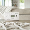 Kidde K10LLDCO 10 Year Digital Carbon Monoxide Alarm on a table with a beige sofa and blanket in the background
