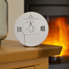 kidde k10sco combined smoke co alarm on a wooden table near a lit wood burner