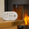 Kidde K5CO Carbon Monoxide Alarm on a wooden table with a fireplace burning in the background
