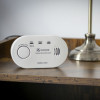 Kidde K5CO Carbon Monoxide Alarm placed on a wooden surface next to a metal lamp