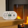 Kidde K5DCO Digital Carbon Monoxide Alarm on a wooden table with a fireplace burning in the background