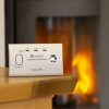 Kidde K7CO Travel Carbon Monoxide Alarm on a wooden table with a fireplace burning in the background