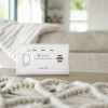 Kidde K7CO Travel Carbon Monoxide Alarm on a table with a beige sofa and blanket in the background