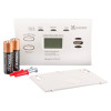 Kidde co digital alarm with two batteries, mounting screws, and a plastic cover plate showing the front panel controls and display
