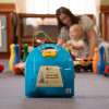 LifeVac wall mounted kit in blue case on the floor with a parent and child playing in the background