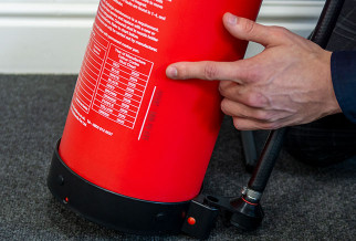 Close-up of a person’s hand pointing at the label on a red P50 Extinguisher 10 Year Refurbishment product