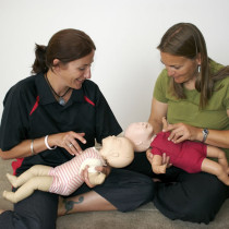 a couple of woman practicing paediatric cpr on baby annes
