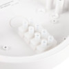 A close-up of a white plastic electrical connector block inside a circular housing, showing multiple cylindrical wire terminals with metal contacts.