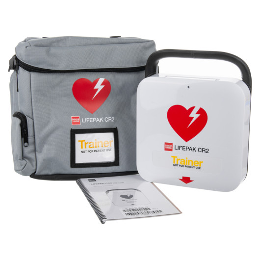 physio control lifepak cr2 trainer unit showing the main device, a grey carry case with heart logo, and an instruction manual