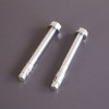 Two silver bolt down screws for the phoenix elara hs3552 security safe on a grey surface