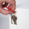 Hand placing a key with a red tag into the key deposit slot of the phoenix cygnus key deposit safe electronic lock