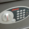 phoenix vela security electronic lock shown from front angled down with keypad and dial on textured grey surface