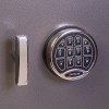 Close up of the front of a phoenix cash deposit security electronic lock showing the keypad and handle