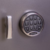 Close up of the front of a phoenix cash deposit security electronic lock keypad and handle on a grey textured surface