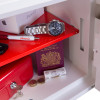 Inside the phoenix fortress 1182 security safe key lock with items including a watch, passport, cash, coins, and a pen on a red shelf