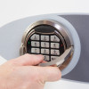 Hand gripping the handle on a phoenix fortress 1183 security safe electronic lock keypad